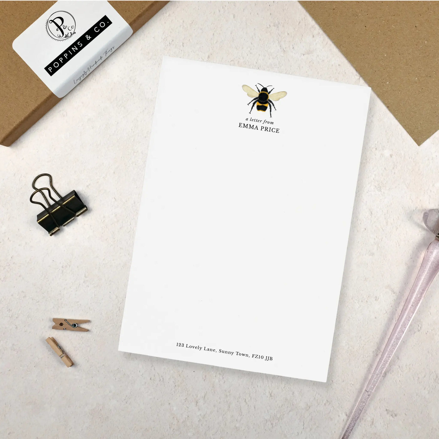 A single sheet of personalised bumblebee writing paper. The writing paper is white and has an illustration of a bee at the top of the page. Italic script reads 'a letter from' with the name 'Emma Price' typed in all caps font below it. At the bottom of the page is a typed address.