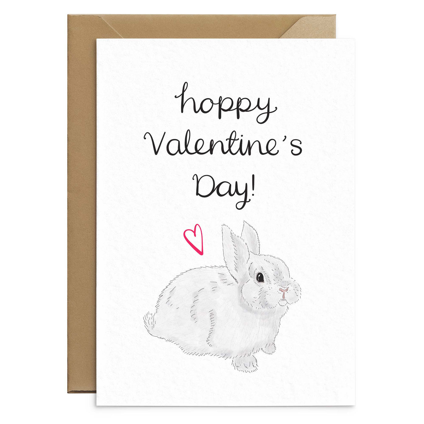 A cute bunny themed valentines day card. A white card has an illustration of a grey/white bunny, a small red love heart and black hand scripted text above that reads 'hoppy valentines day!'. Behind the card is a brown Kraft envelope. Greetings card by Poppins and co.