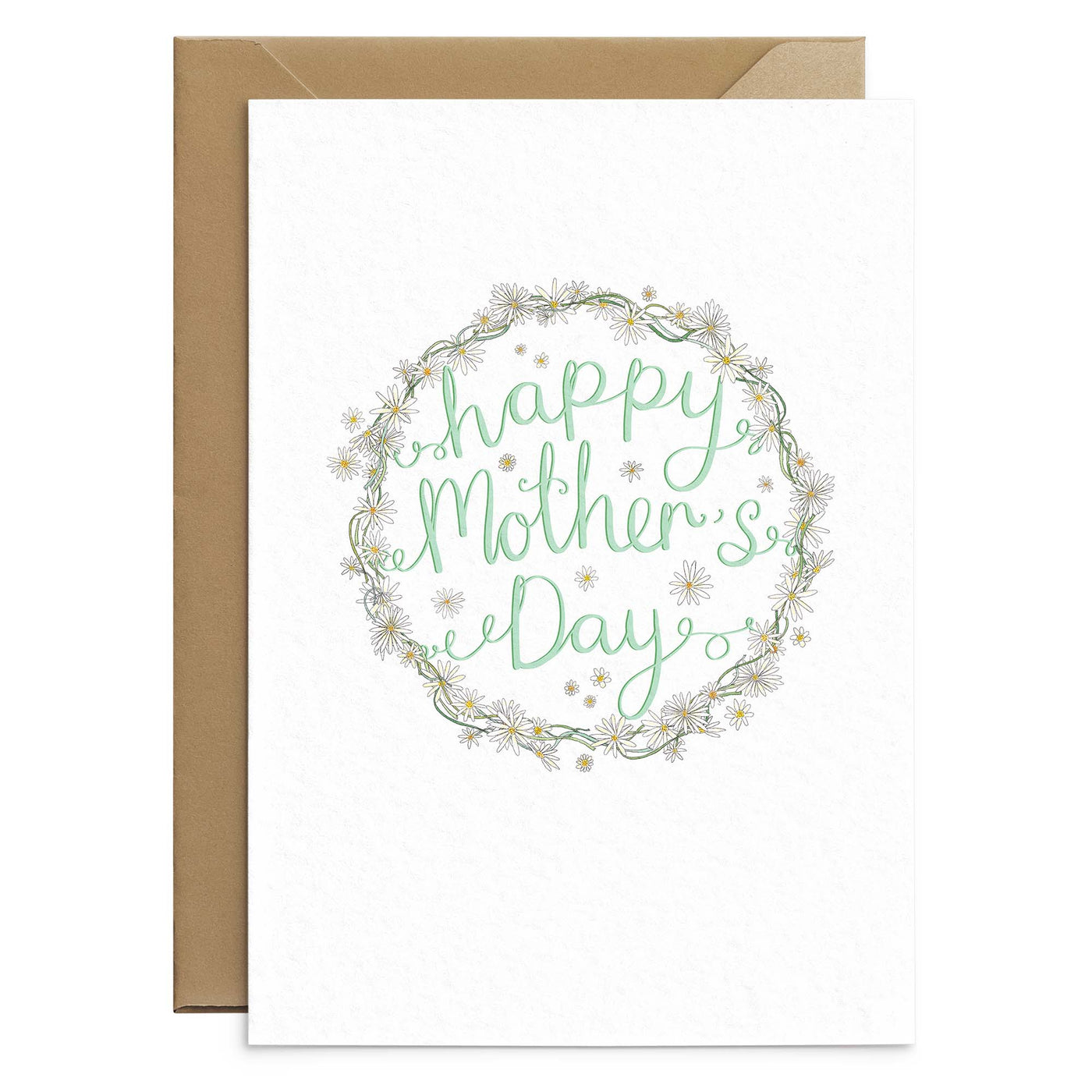 A cute daisy themed greetings card with a unique illustration or a daisy chain wreath and dotted daisy heads around mint green scripted text. text reads 'happy Mother's Day'. the card has a white background and behind it you can the the edge of a brown Kraft envelope. Greetings Card by Poppins and co.