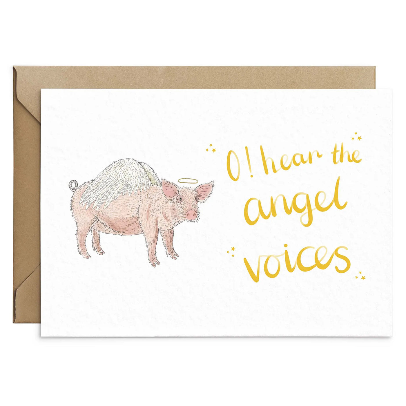 A unique christmas card lays on brown envelope on a white background. The card depicts a whimsical illustration of cute pig with angel wings and a halo.  Hand scripted yellow text reads 'O! hear the angel voices'.