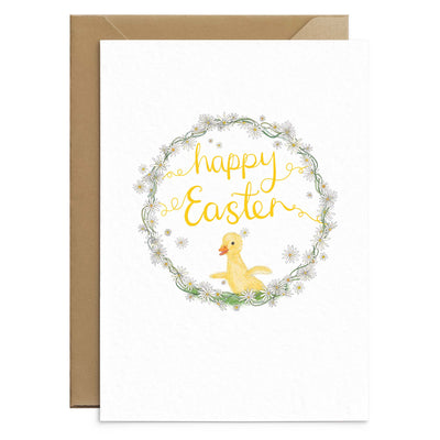A cute easter greetings card featuring a yellow duckling drawn inside a wreath of daisies and completed by hand scripted yellow text that reads 'happy easter'. On a brown recycled envelopes. Greetings cards by Poppins and co.