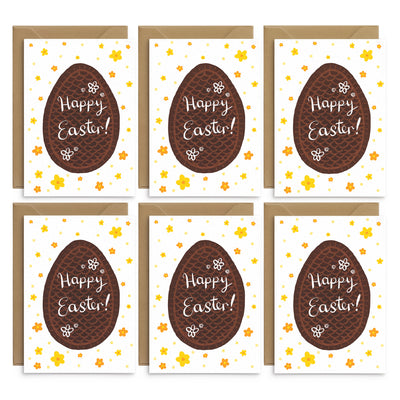 A set of classic easter greetings card featuring chocolate eggs and yellow daisies. Completed by white hand scripted text on the egg illustration that reads 'happy easter'. 6 white greetings cards laid out on top of 6 brown recycled envelopes. Easter greetings cards by Poppins and co.