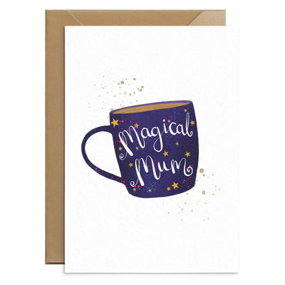 White greetings card with an illustration of a dark blue and purple coffee or tea mug cover with yellow stars. drink splashes above and below the mug. white script text on the mug reads 'magical mum'. Behind the card there is a brown Kraft envelope. Greetings Card by Poppins and co.