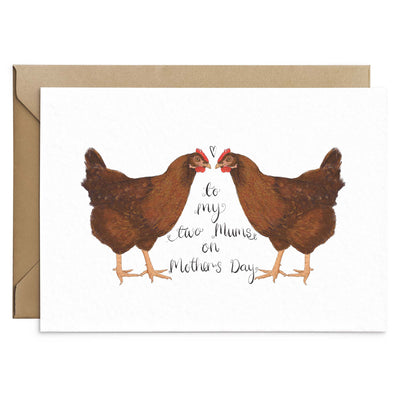 Chicken themed mothers day card. Black scripted text reads 'To my two mums on Mothers Day Card'. Illustration of a mirror image of hens facing towards each other. The background of the card is white and the edges of a brown Kraft envelope can be seen. Greetings Card by Poppins & Co.