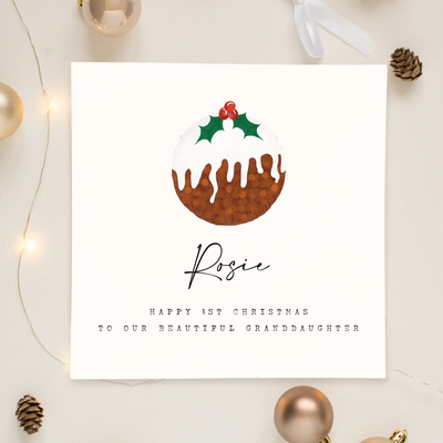 A personalised square Christmas greetings card featuring a unique illustration of a Christmas pudding and personalisable text reading 'Rosie, happy 1st christmas to our beautiful granddaughter'.