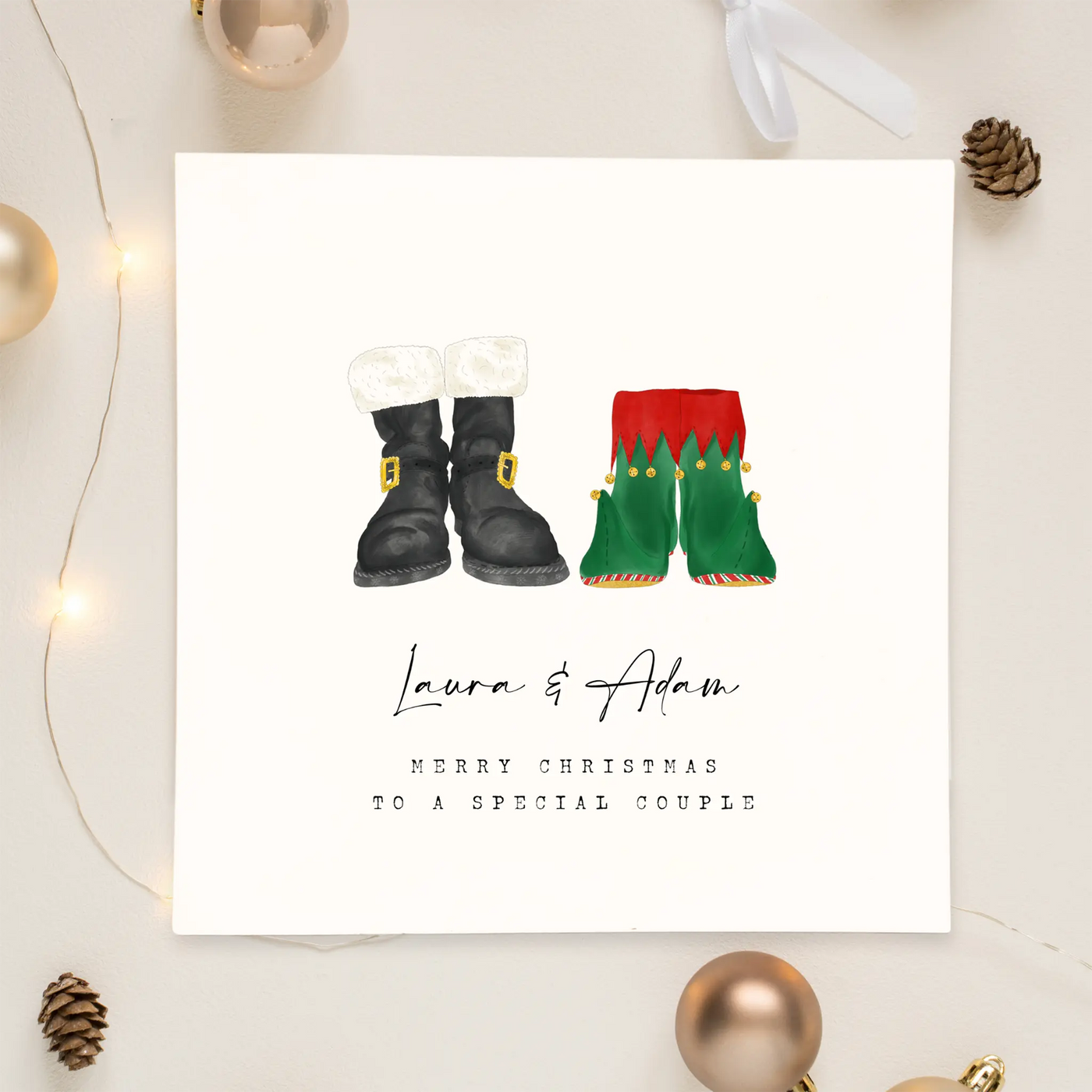 A square christmas card featuring unique watercolour illustrations of a pair of Santa boots and elf boots side beside. Beneath the boots personalised text reads 'Laura and Adam - merry christmas to a special couple.