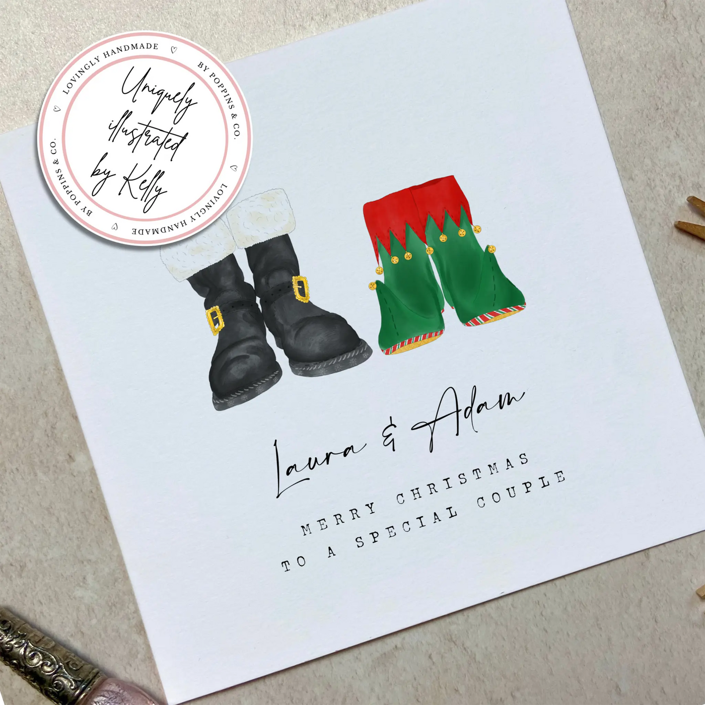 A square christmas card featuring unique watercolour illustrations of a pair of Santa boots and elf boots side beside. Beneath the boots personalised text reads 'Laura and Adam - merry christmas to a special couple.