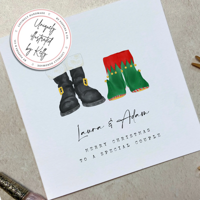 A square christmas card featuring unique watercolour illustrations of a pair of Santa boots and elf boots side beside. Beneath the boots personalised text reads 'Laura and Adam - merry christmas to a special couple.