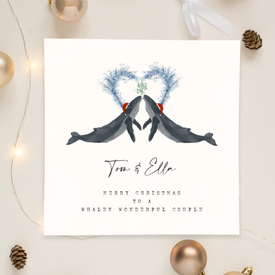 A square christmas card for a wonderful couple featuring unique watercolour illustrations of a pair of humpback whales in christmas hats. Beneath the birds personalised text reads 'Tom and Ella - merry Christmas to a whaley wonderful couple'