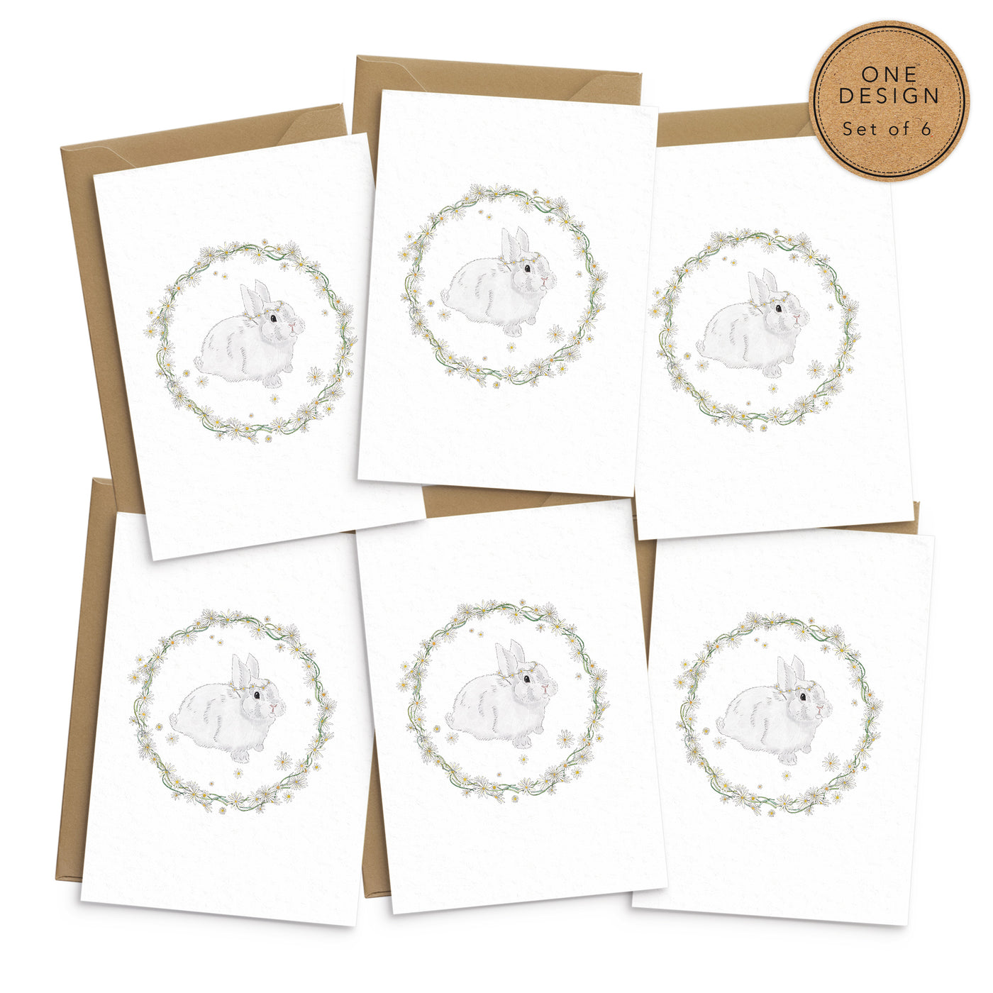 A set of 6 spring themed greetings cards featuring a white bunny wearing a daisy crown pictured inside a rather made of daisies and greenery. No text. Photo shows 6 cards laid out on top of recycled brown envelopes. Easter greetings cards by Poppins and co.
