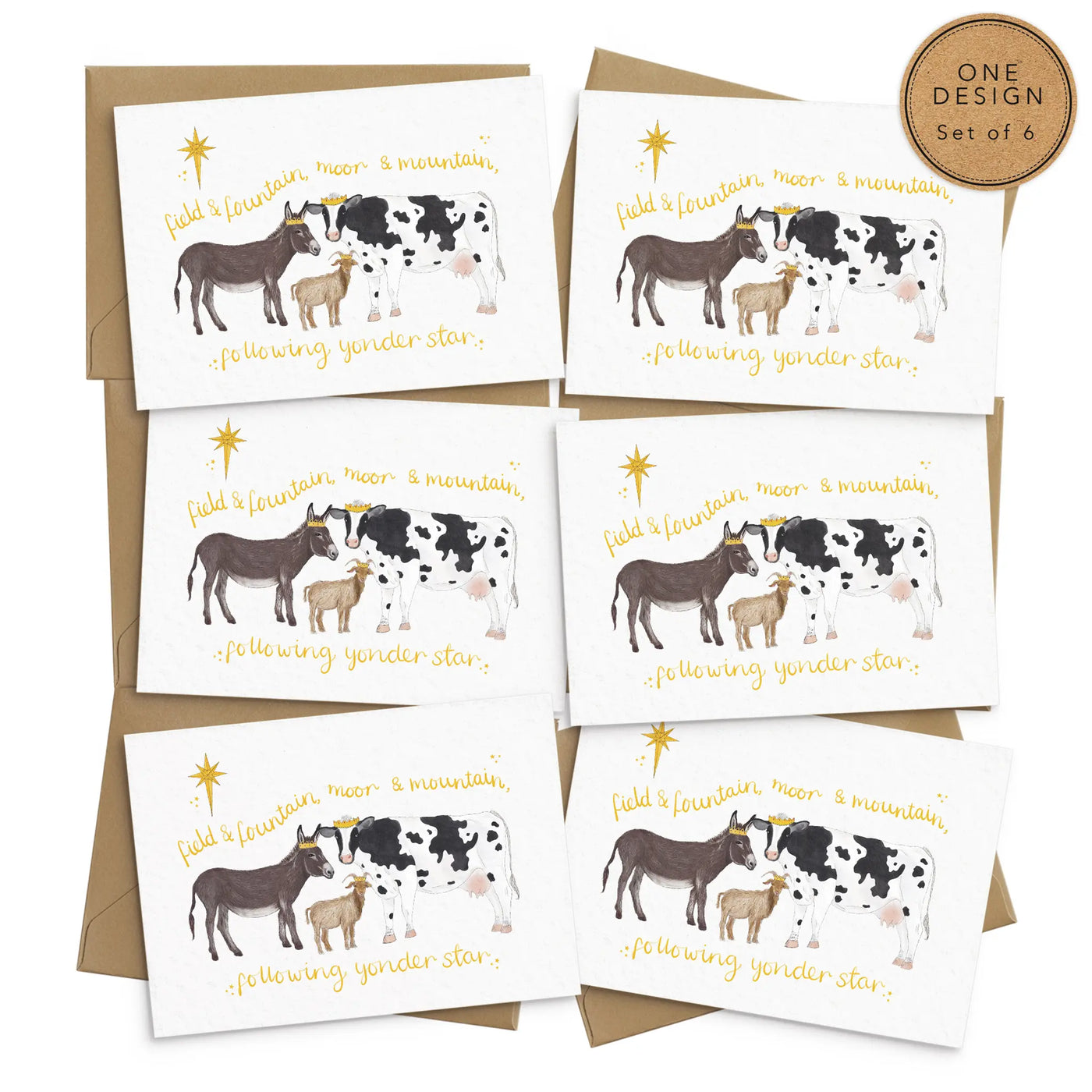 A unique set of 6 christmas cards lays on brown envelopes on a white background. The card depicts a whimsical illustration farm animals as the three wise men- a donkey, goat and cow.  Hand scripted yellow text reads 'field and fountain, moor and mountain, following yonder star'.