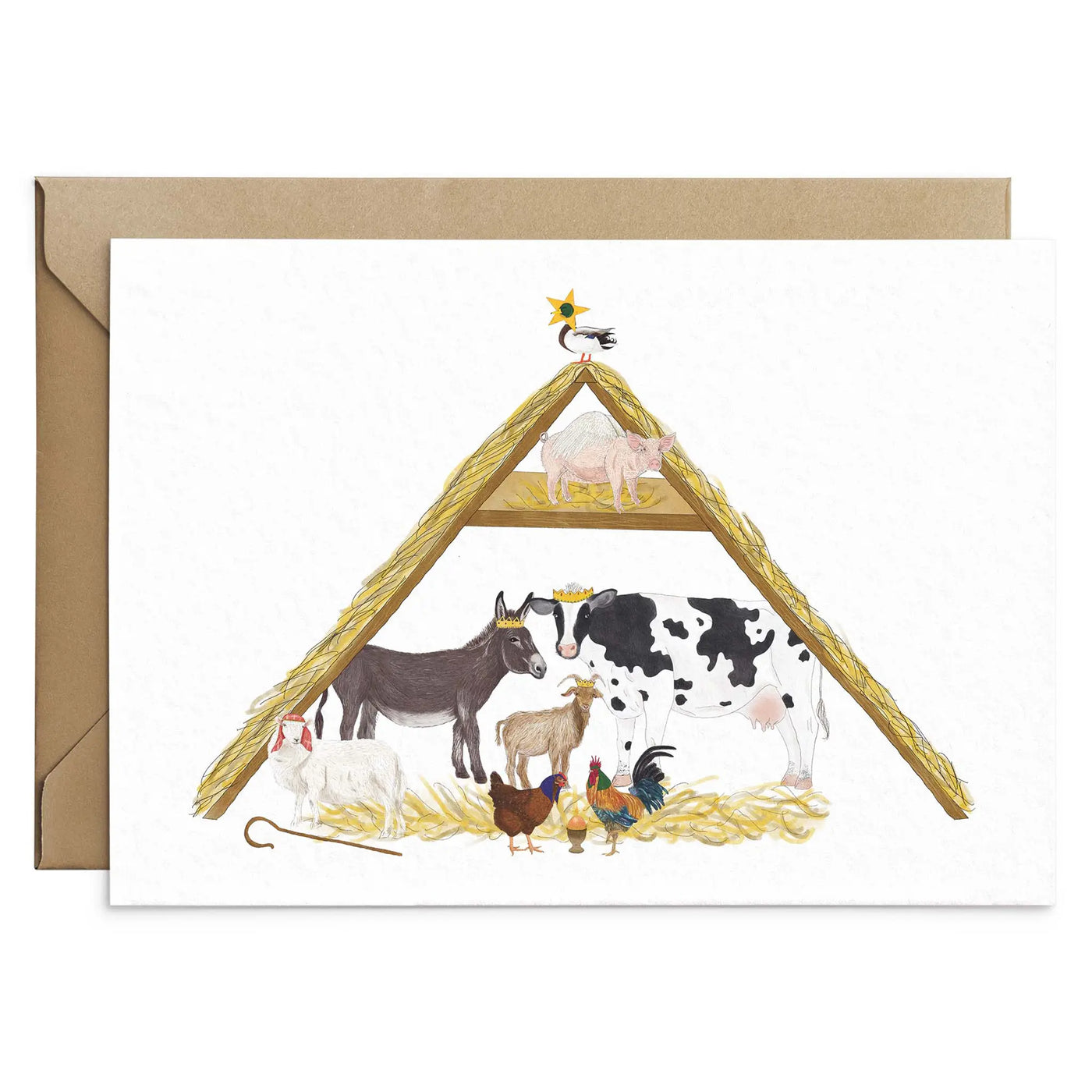 A unique christmas card lays on a table surrounded by christmas lights and ornaments. The card depicts a whimsical illustration of nativity scene where all the roles are played by farm yard animals.  Hand scripted yellow text read.