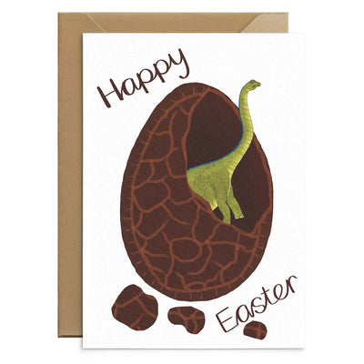 An unusual easter card for kids featuring a green diplodocus hatching from inside chocolate easter egg. Brown text reads 'happy easter' on each card. Illustration on white A6 card with recycled envelopes. Easter cards by Poppins and co.