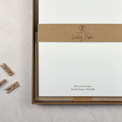 packaged writing paper in a brown kraft box. A brown kraft belly band reads 'poppins and co writing paper'. An address is typed at the bottom of the paper.