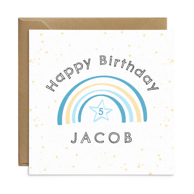 Personalised blue rainbow birthday card for children. A square card with pale stars in the back ground and a pastel pink rainbow. The rainbow has the number 4 below and the text can be personalised - text reads Happy Birthday Olivia. Birthday card by Poppins and co.